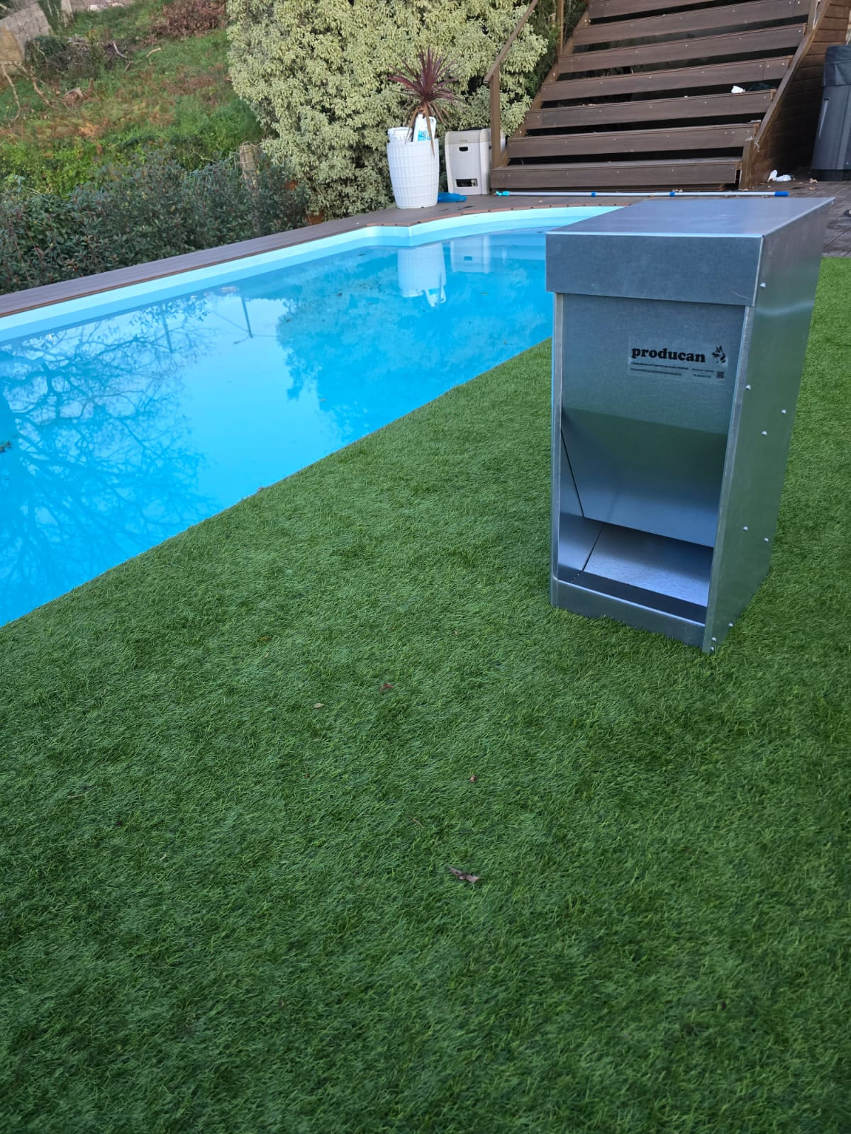 Comedero automático Producan colocado sobre el césped junto a una piscina